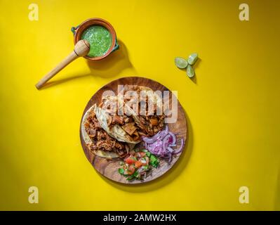 Tacos messicani delle carnitas con salsa, limoni, insalata e cipolla piccante Foto Stock