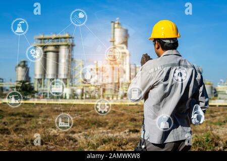 Imprenditore Foreman lavora con la raffineria di petrolio pianta del settore industria e le icone. In fabbrica la notte come la comunicazione di energia. Tecnologia Smart 4.0 Foto Stock