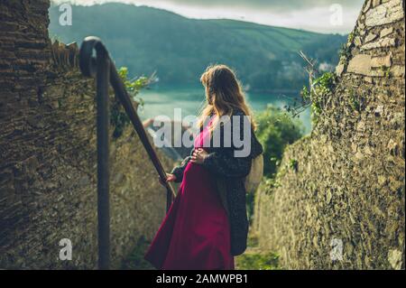 Una giovane donna incinta sta camminando su alcune scale all'aperto in un piccolo villaggio in una giornata invernale Foto Stock