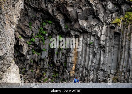 Myrdal, Islanda - 14 giugno 2018: Spiaggia di sabbia nera di Reynisfjara basalto formazioni rocciose vulcaniche con persone turistiche seduto in grotta Foto Stock