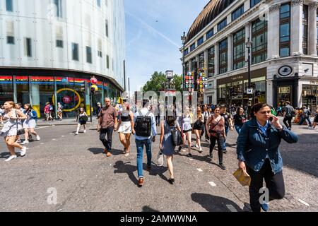Londra, Regno Unito - 24 giugno 2018: Molti turisti che camminano per lo shopping di strada nei negozi di Leicester Square durante il giorno in città attraversando l'incrocio Foto Stock