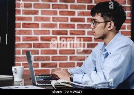 Imprenditore asiatico di Woking con il computer portatile e il foglio di lavoro sulla scrivania in ufficio.workflow digitale business online il concetto di stile di vita Foto Stock