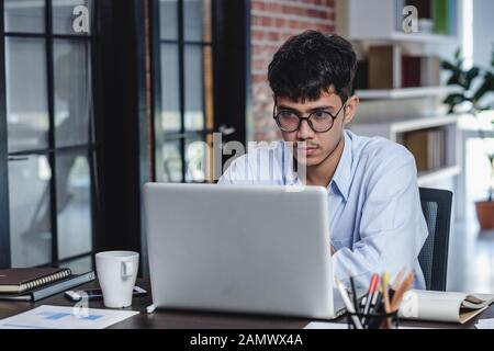 Imprenditore asiatico di Woking con il computer portatile e il foglio di lavoro sulla scrivania in ufficio.workflow digitale business online il concetto di stile di vita Foto Stock