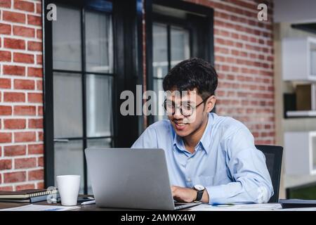 Imprenditore asiatico di Woking con il computer portatile e il foglio di lavoro sulla scrivania in ufficio.workflow digitale business online il concetto di stile di vita Foto Stock
