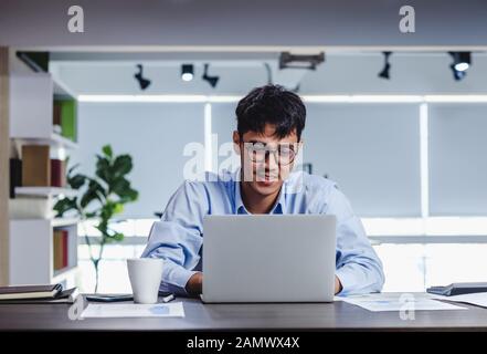 Imprenditore asiatico di Woking con il computer portatile e il foglio di lavoro sulla scrivania in ufficio.workflow digitale business online il concetto di stile di vita Foto Stock