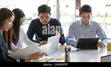 Tagliate il colpo di un gruppo di persone di business consulting il loro progetto in modo semplice sala riunioni Foto Stock