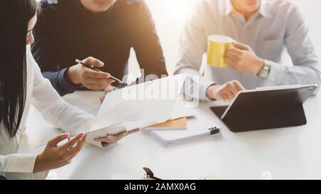 Ritagliato shot del gruppo aziendale a discutere il loro progetto in semplici co e spazio di lavoro Foto Stock