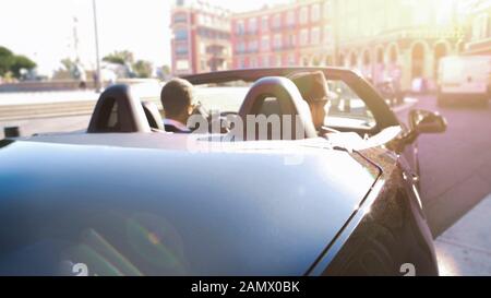 Elegante auto con tetto aperto lungo la strada vuota della città turistica, viaggio di lusso Foto Stock