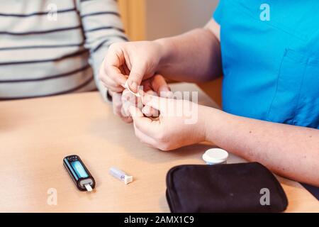 Infermiere amministra il test del diabete a senior in casa di cura Foto Stock