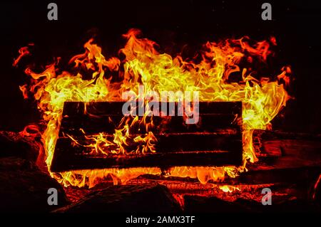 Un pallet di legno brucia sul fuoco all'aperto nella tarda sera Foto Stock