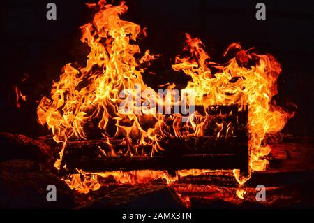 Un pallet di legno brucia sul fuoco all'aperto nella tarda sera Foto Stock