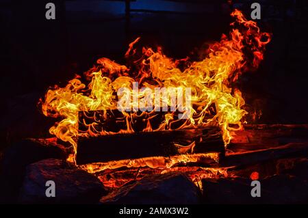 Un pallet di legno brucia sul fuoco all'aperto nella tarda sera Foto Stock