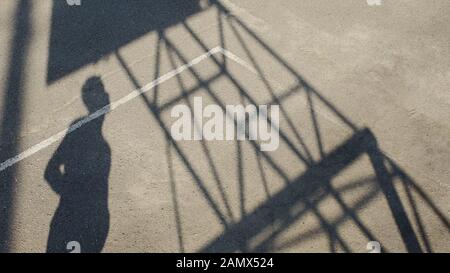 Ombra di sportivo in piedi sullo stadio e guardando il basket cerchio, lo sport Foto Stock