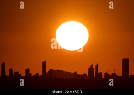 Tramonto con grande sole su Benidorm skyline della città di Alicante Foto Stock