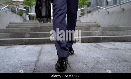 Il dipendente cammina giù per le scale, lascia il business center e termina la settimana lavorativa Foto Stock