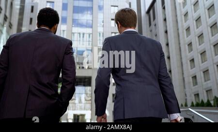 I colleghi multirazziali si avvicinano al business center, discutendo il successo del progetto Foto Stock