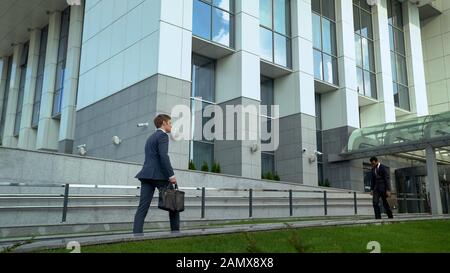 Dipendenti depressi mulatto che lasciano il business center, europei che camminano all'interno Foto Stock