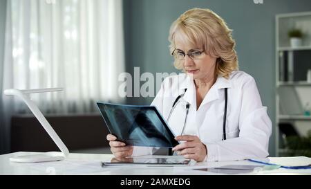 Medico che esamina la scansione, esamina i raggi X dei polmoni del paziente, l'assistenza sanitaria, la medicina Foto Stock