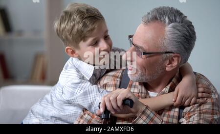 Nipote che abbraccia il nonno con amore, preziosi minuti di famiglia, assistenza agli anziani Foto Stock