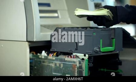 Uomo di sicurezza che apre bancomat sicuro, prendendo fuori bundle di dollari, contanti in transito Foto Stock