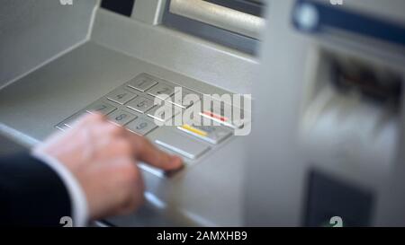 Closeup di uomo d'affari inserendo il suo codice pin sulla tastiera di ATM, servizio bancario Foto Stock