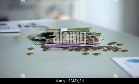 Pile di banconote e monete in tavola, valuta estera, retribuzioni, contanti Foto Stock