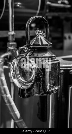 Primo piano in bianco e nero della vecchia lampada d'epoca sul motore di trazione inglese conservato in mostra alla ferrovia a vapore della Severn Valley Heritage. Lanterna in vecchio stile. Foto Stock