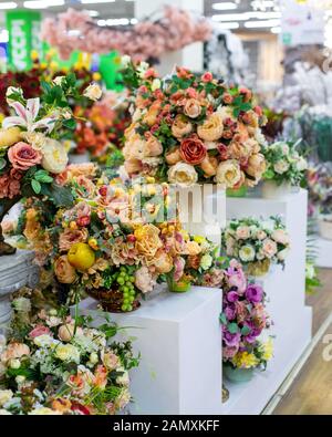 Bouquet di rose artificiali con foglie, uva e mele. Interior design, decorazione fiori artificiali rose . Sfondo verticale fiore Foto Stock