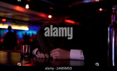 Uomo ubriaco che dorme sul banco del bar, depressione sofferente, concetto di abuso di alcool Foto Stock