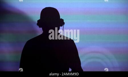 Silhouette uomo DJ a muro, esecuzione per festa, danza per la musica, vista posteriore Foto Stock