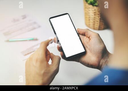 uomo che usa lo smartphone per transazioni finanziarie. tenere il telefono con lo schermo vuoto in mano Foto Stock