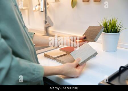 disegno interno della cucina - donna che seleziona la struttura del materiale del mobile Foto Stock