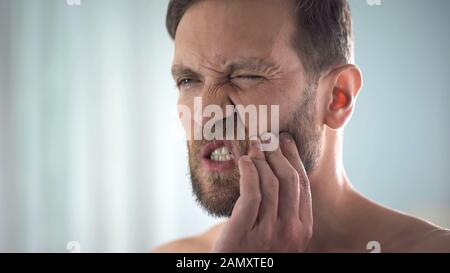 L'uomo sente forte dolore dentale, forte dolore dentale, infiammazione della polpa, decadimento Foto Stock