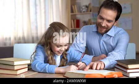 Sorridente tutor che aiuta la bambina ad imparare nuove parole, fare i compiti, l'istruzione Foto Stock