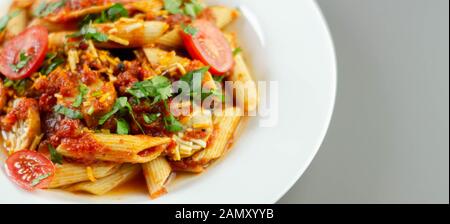 Penne pasta con una ricca salsa di pomodoro e fette di British insaccato di maiale conditi con formaggio Cheddar, cibo italiano Foto Stock