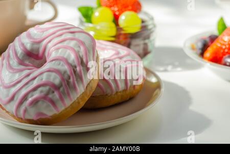 Ciambella con aroma di lampone riempimento, guarnita con bianco e rosa, glassa dolce ciambella Foto Stock