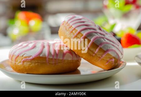 Ciambella con aroma di lampone riempimento, guarnita con bianco e rosa, glassa dolce ciambella Foto Stock