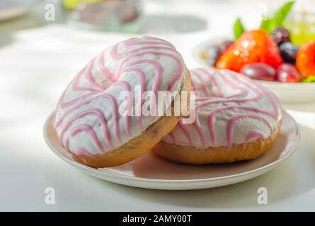Ciambella con aroma di lampone riempimento, guarnita con bianco e rosa, glassa dolce ciambella Foto Stock