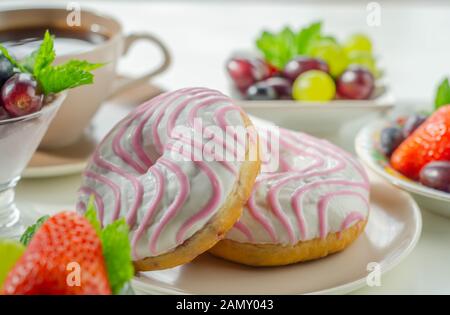 Ciambella con aroma di lampone riempimento, guarnita con bianco e rosa, glassa dolce ciambella Foto Stock