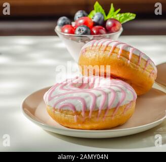 Ciambella con aroma di lampone riempimento, guarnita con bianco e rosa, glassa dolce ciambella Foto Stock