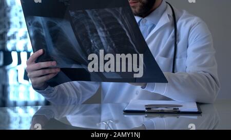 Pulmonologo maschile che guarda ai polmoni raggi X, osservazioni e diagnosi, ospedale Foto Stock