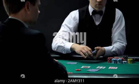 Croupier di casino maschio che si occupano di carte per l'uomo d'affari, la possibilità di vincere al gioco di poker Foto Stock