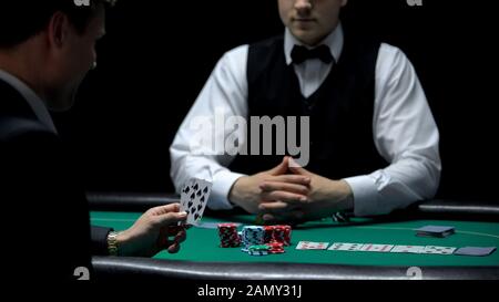 Uomo d'affari troppo sicuro che ha una cattiva combinazione di mano, ma fare la scommessa al poker Foto Stock