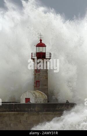 Porto, Portogallo - 7 Febbraio 2016: persone negligente nel mezzo della tempesta di mare. Fiume Douro bocca vecchio faro. Foto Stock