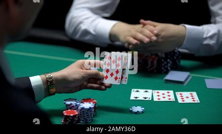 Uomo d'affari che gioca a poker al casinò che controlla la combinazione di carte, gioco d'azzardo Foto Stock