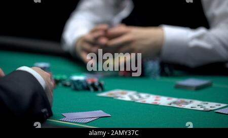 Croupier del casinò in attesa del giocatore di poker per rivelare la combinazione di carte, il gioco d'azzardo Foto Stock