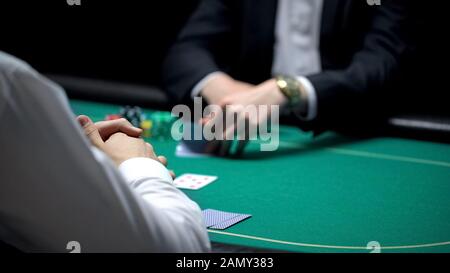 Giocatore di poker che controlla la combinazione di carte mentre il croupier maschio in attesa, il gioco d'azzardo Foto Stock