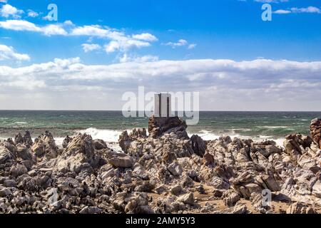 Rovina di una piccola torre abbandonata, costruita su una roccia vicino al surf del mare, costa rocciosa vicino Betty's Bay, Sud Africa Foto Stock