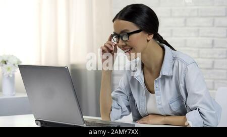 Felice donna sorridente, lettura messaggi in rete sociale, on-line chat Foto Stock