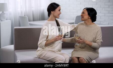 Due felici donne asiatiche bere vino bianco, celebrazione della vittoria, partnership Foto Stock